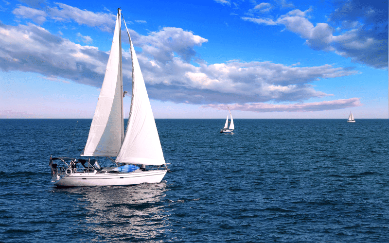 Sailing as a Paralympic sport: A sailboat glides across the water, with a person in a wheelchair on the dock watching